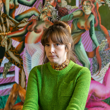 Jessie Makinson wearing a green jumper in front of a painting 