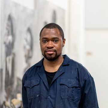 headshot of artist in his studio wearing dark blue overalls