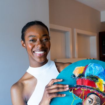 Ekene Manduka smiling and holding a tondo painting