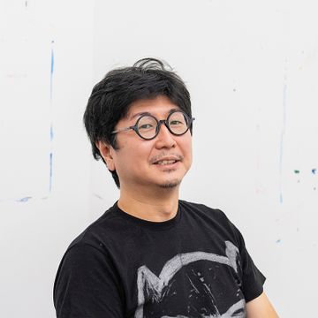 Susumu Kamijo in a black tshirt and glasses smiling