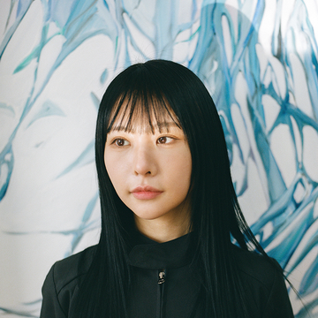 artist Minhee Kim wearing black and looking into the distance in her studio
