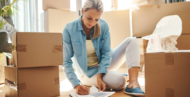 Žádost o hypotéku krok za krokem - krabice, obývák, žena vyplňuje formulář