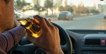 Muž pije pivo při řízení auta