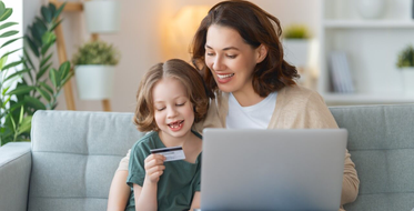 Účty a platební karty pro děti - Maminka s holčičkou sedí na gauči v obýváku, notebook, platební karta