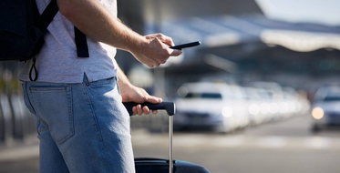 Muž na letišti s kufrem a telefonem, který používá