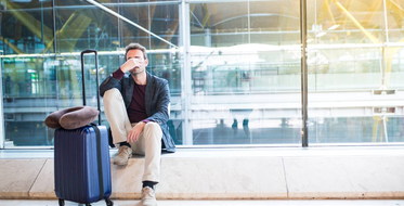 Ospalý muž s kufrem na letišti - jet lag