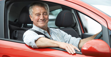Starší muž v červeném autě