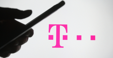 Ruka s mobilním telefonem v ruce, v pozadí logo T-Mobile