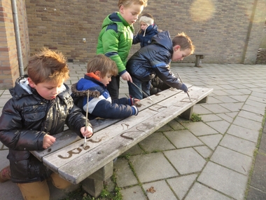 Kleuters verven letters op bevroren bankjes met warm water en een kwast, kleuteridee.nl