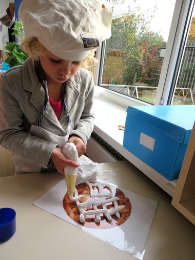 Scheerschuim spuiten op een gelamineerd taart, kleuteridee.nl, thema bakker voor kleuters