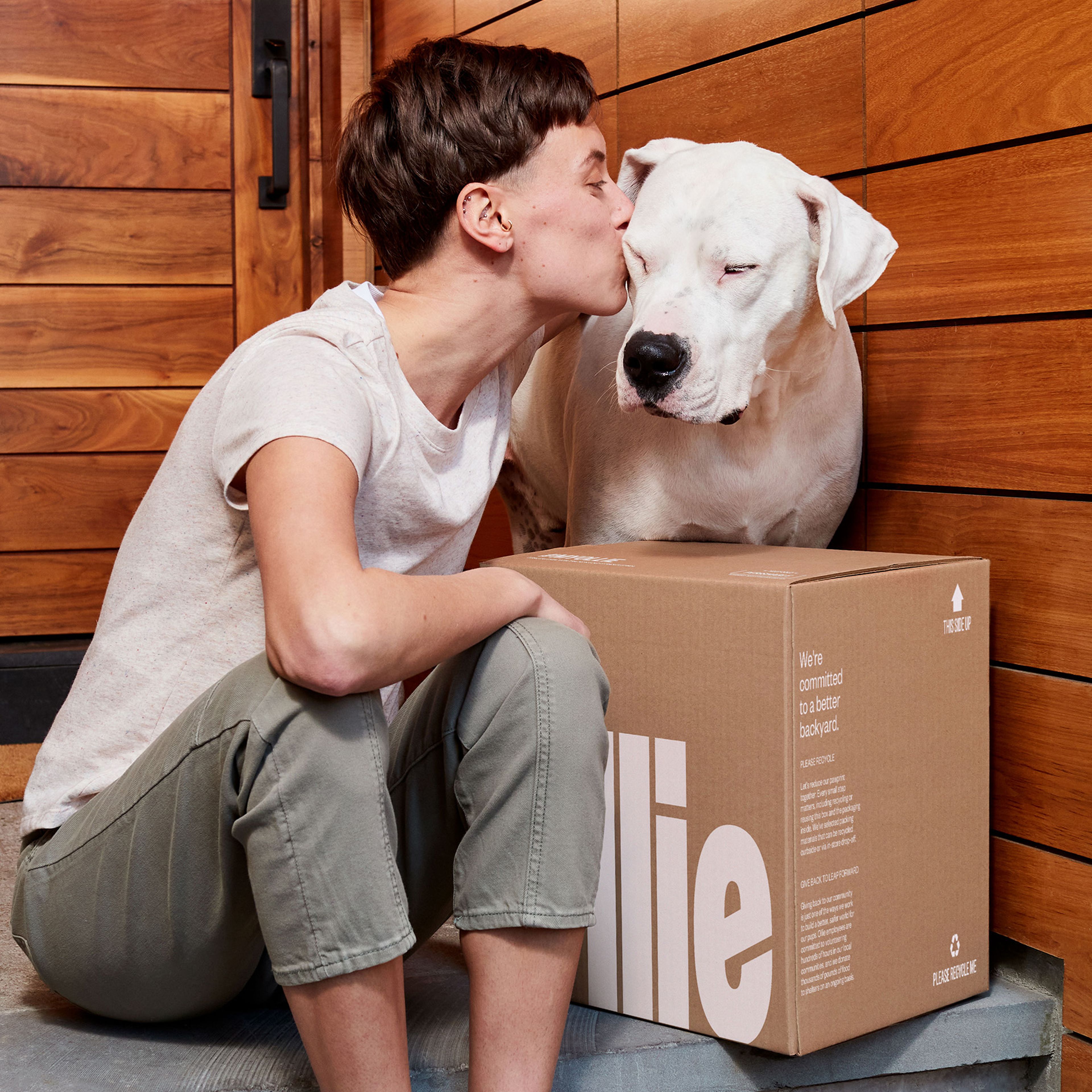 Dog owner kissing her dog on the head with a box of Ollie at the front porch.
