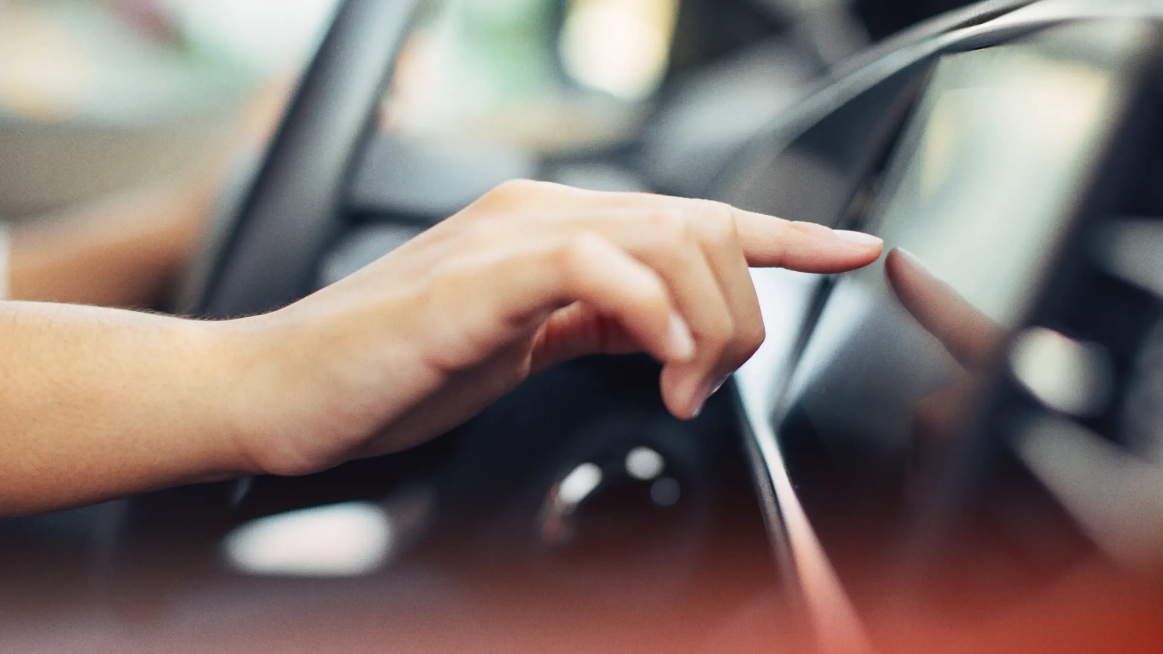 Hand reaching for a car dashboard touchscreen, UX sound design that guides users through in-vehicle interfaces