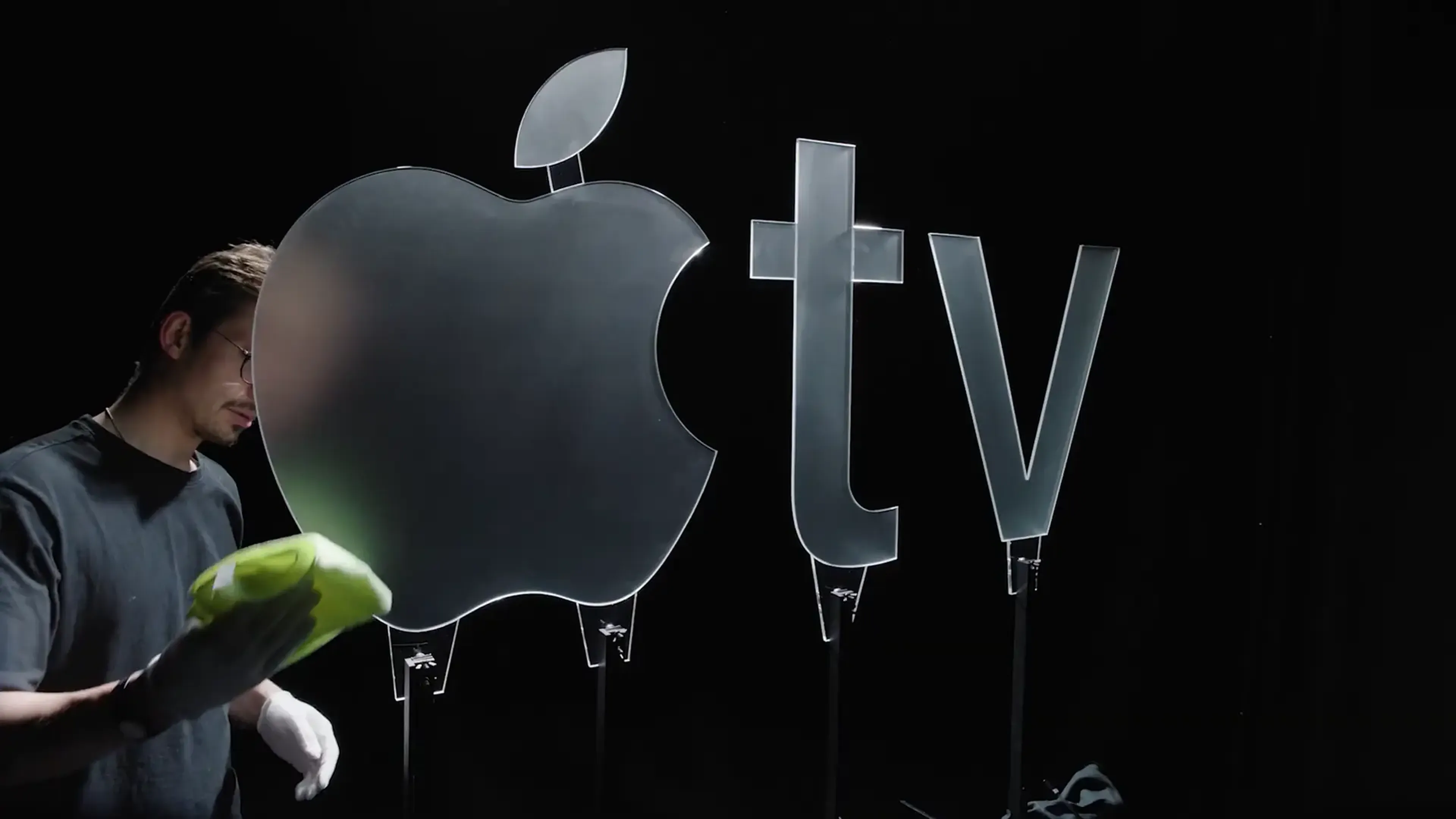 Craftsman polishing a glass Apple TV logo, showing how far brand identity has moved beyond the jingle