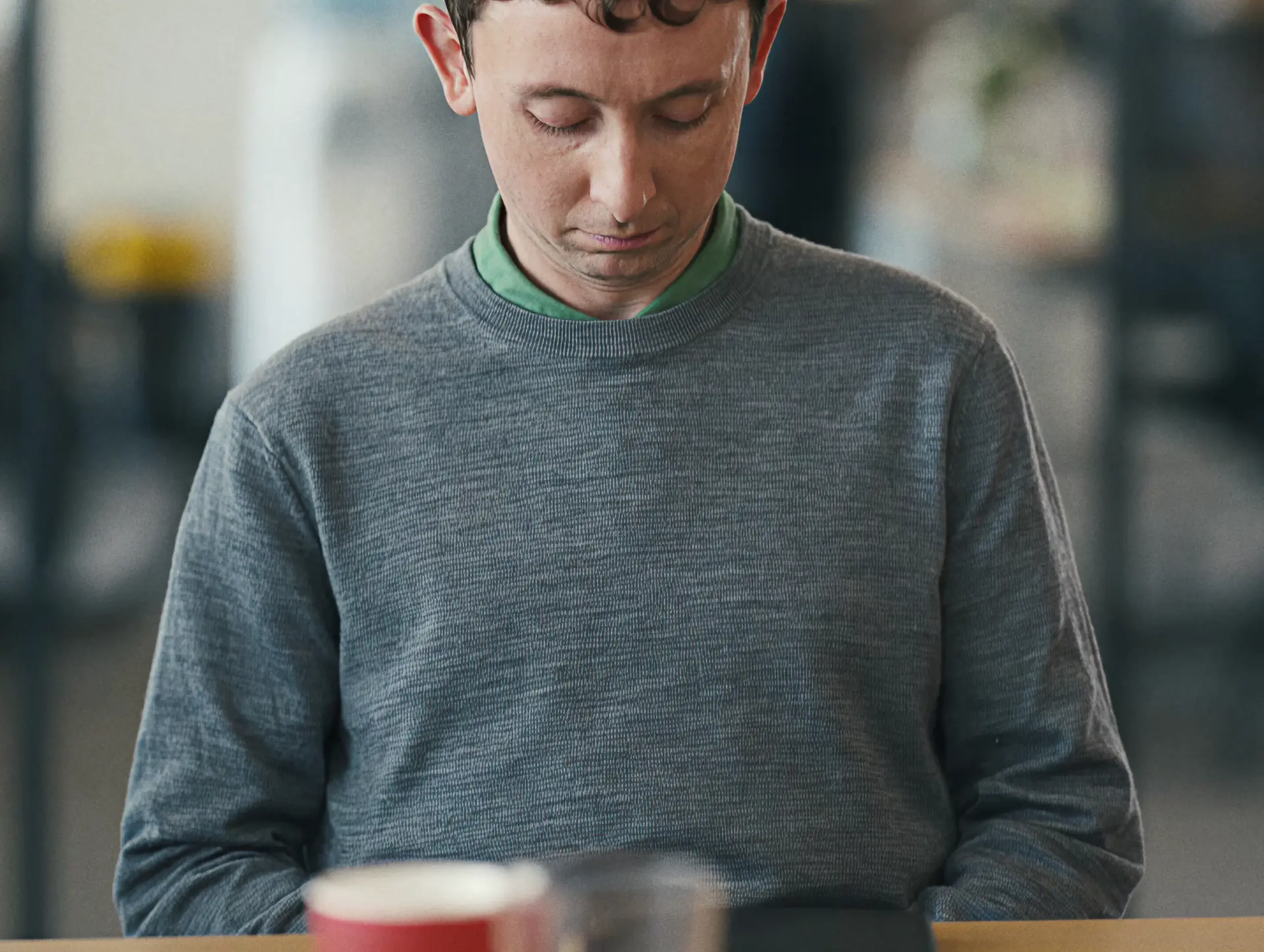 Man in a grey sweater with a McDonald's drink in a bright restaurant, from the Sound of McDonald's