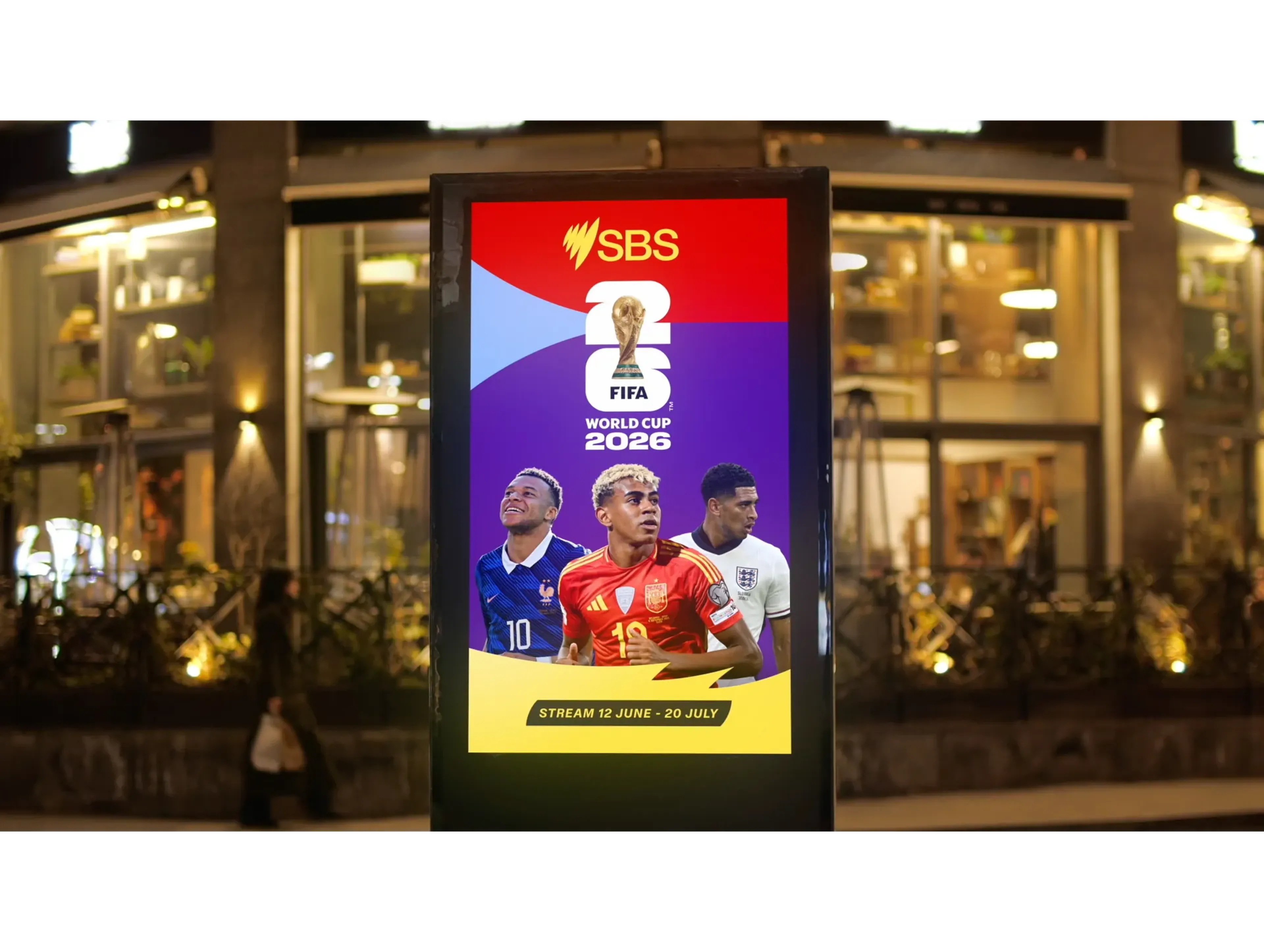 SBS FIFA World Cup 2026 digital poster on a city street at night, the broadcaster's sound carried into live sport