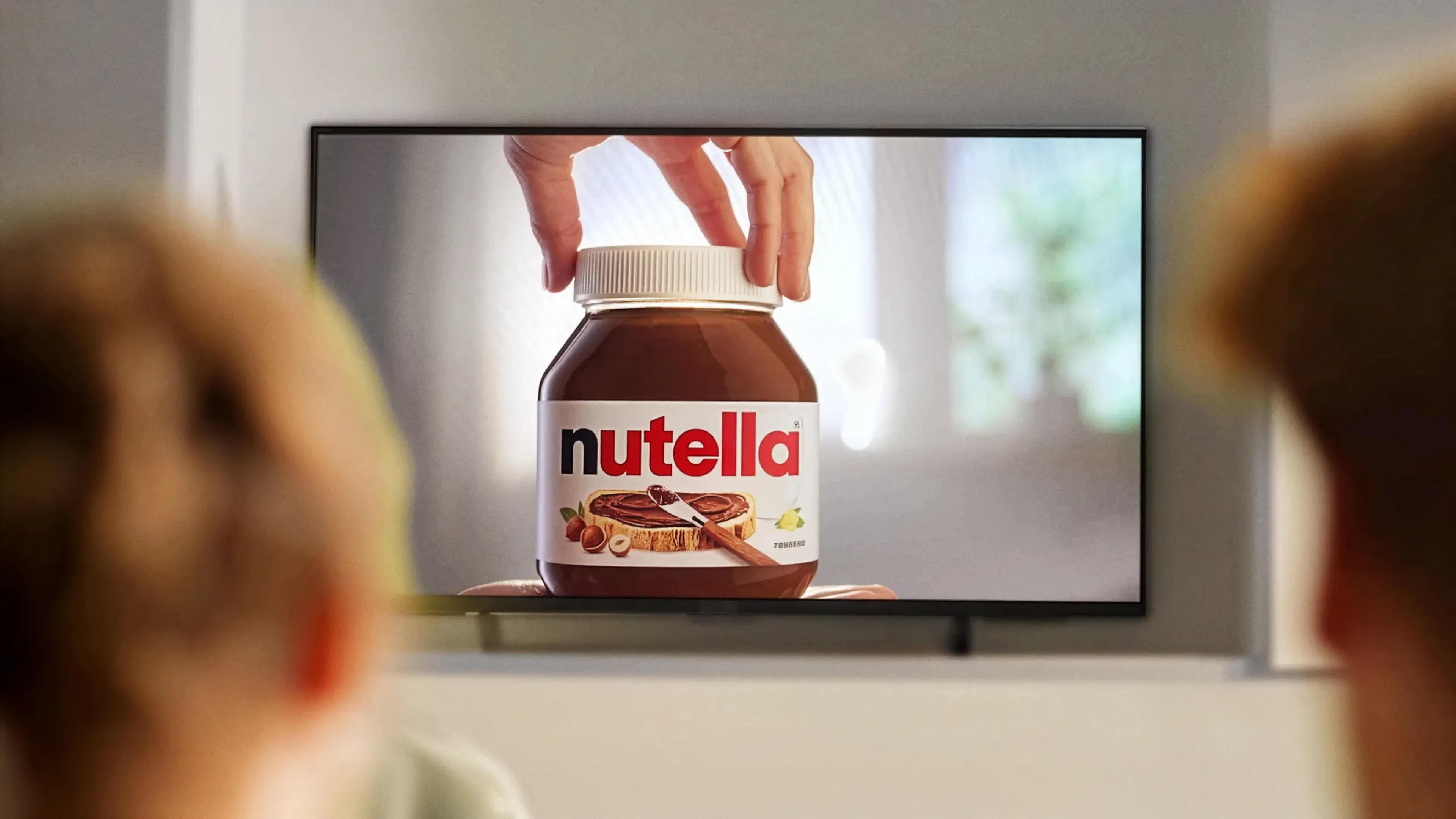 Two people watching a Nutella advert on a living room television, the kind of TV spot MassiveMusic scores