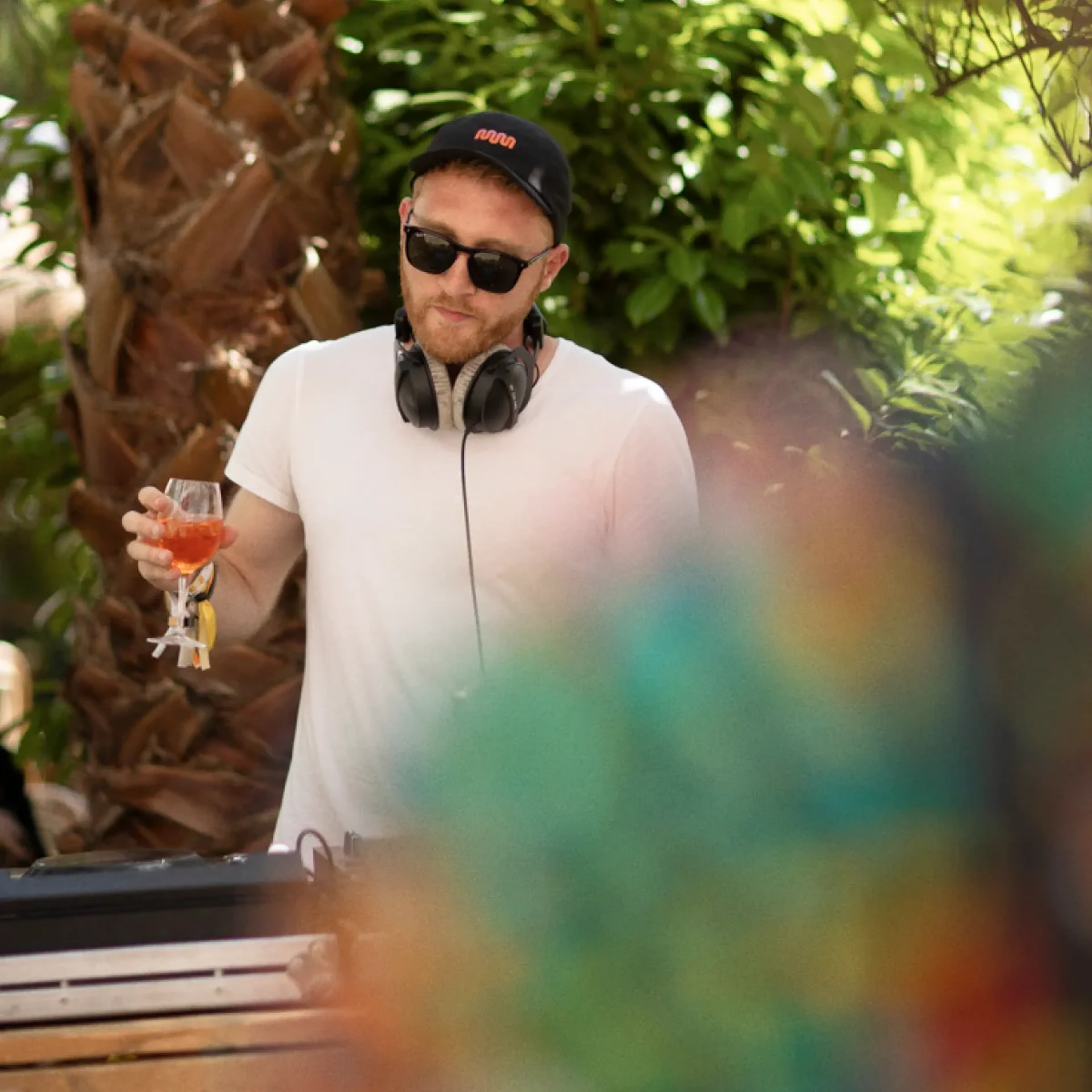 MassiveMusic team member DJing in a branded cap at an outdoor summer party