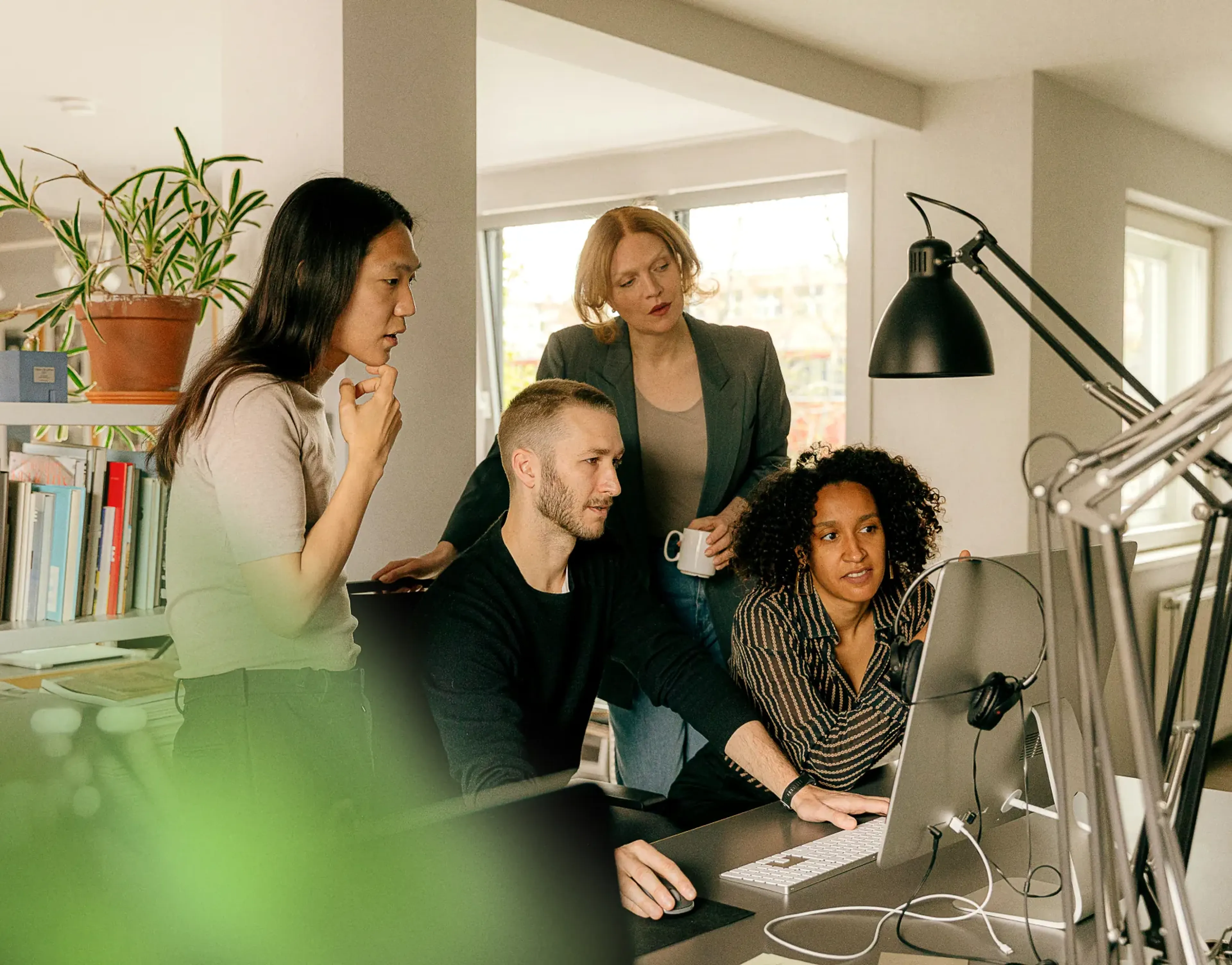 Four colleagues reviewing a screen in a bright office, building a consistent audio strategy for brands and agencies