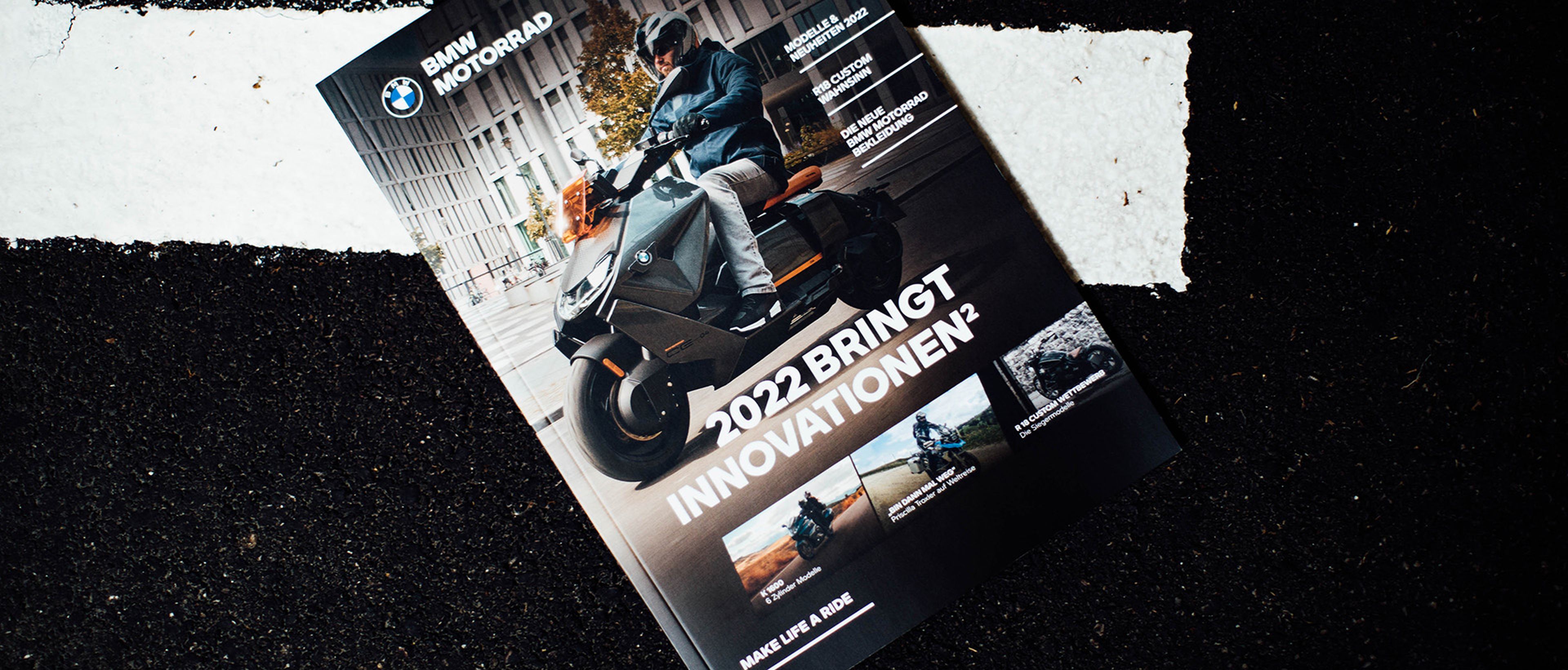 BMW Motorrad Magazin 2022 auf schwarzem Asphalt liegend