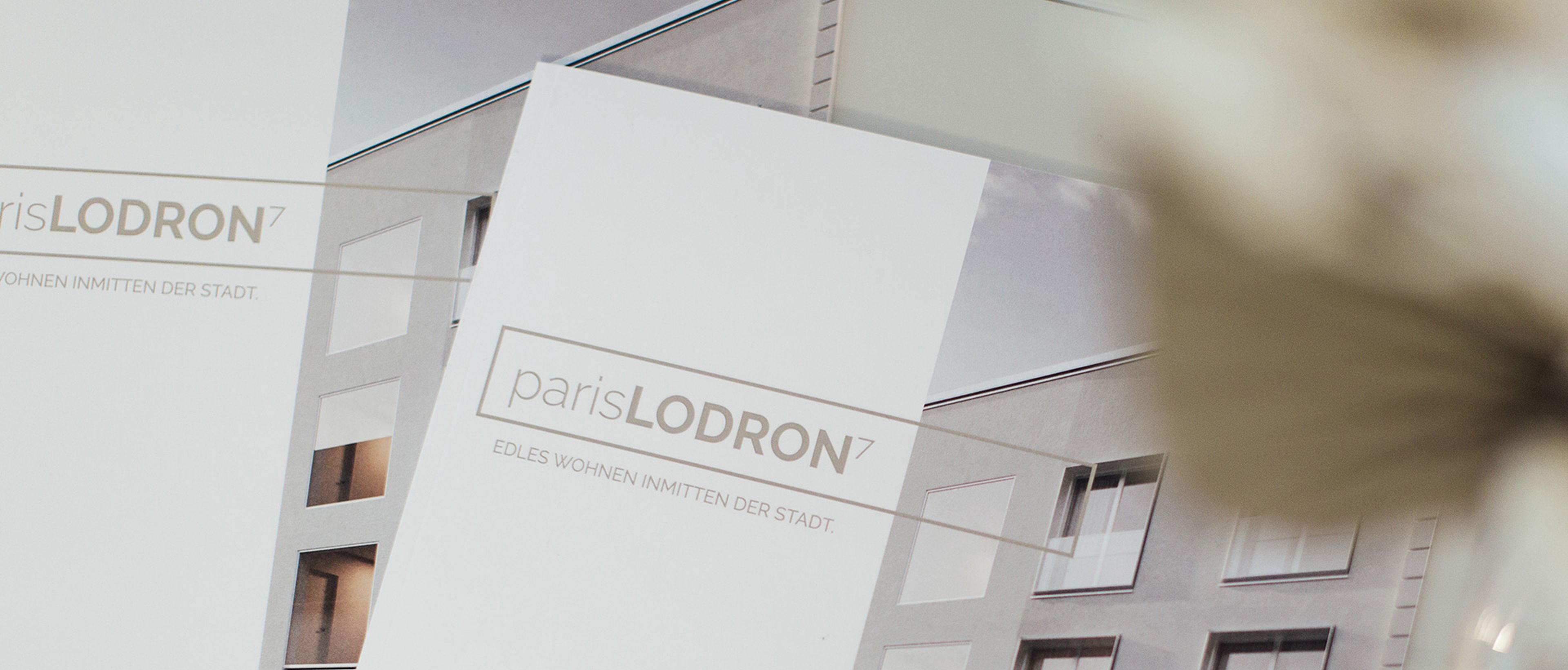 Zwei Folder zur Bauprojekt Wohnzone Paris Lodron 7 liegen auf einem Tisch