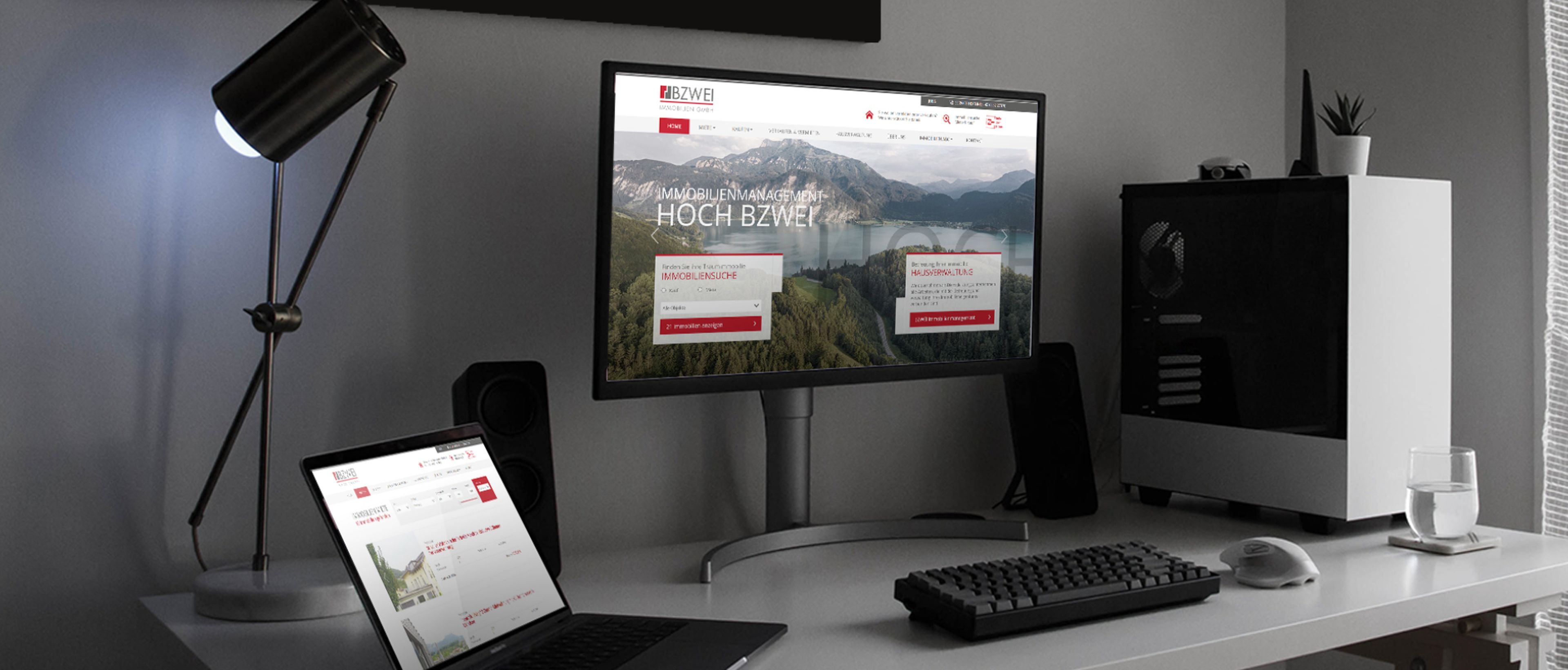 Schreibtisch mit Laptop und Monitor mit BZWEI Immobilien Webseite