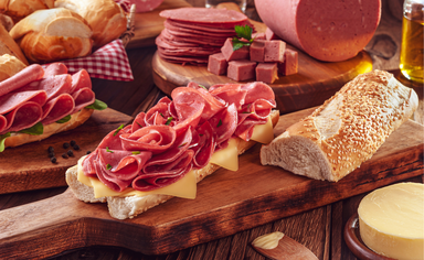Mortadella sandwich with butter, bread and spices on wood cutting board