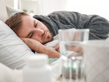 Mann liegt mit Grippe oder Erkältung im Bett