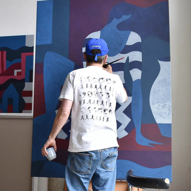 Piet Parra paints with his back to the camera wearing a blue cap