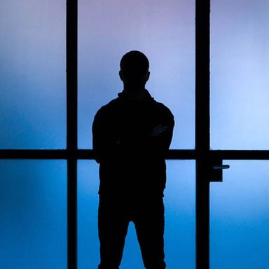 silhouette of Felipe Pantone with blue lit panes of glass behind him