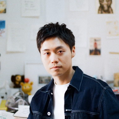 artist Chen Wei Ting wearing a denim jacket and seated in his studio