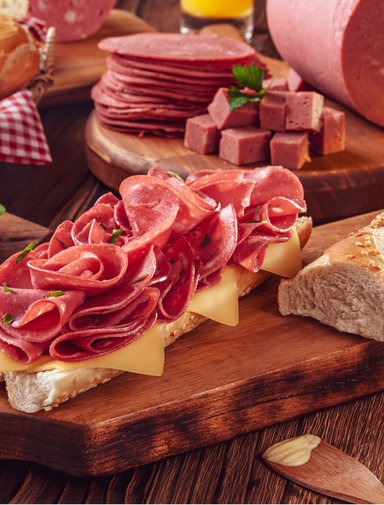 Mortadella sandwich with butter, bread and spices on wood cutting board