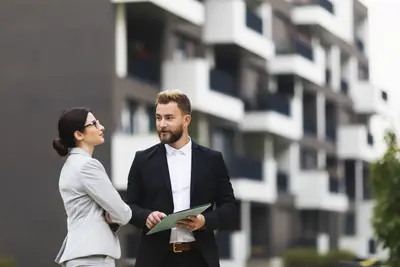 Teileigentum: Ein Makler spricht mit einer Geschäftsfrau über ihr künftiges Teileigentum an einer Immobilie.