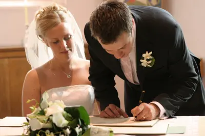 Ein Brautpaar unterschreibt beim Standesamt: Sie leben nun in einer Zugewinngemeinschaft.
