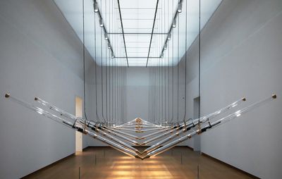 large installation fills entire room as it hangs on ropes from the ceiling so that it is lifted above the ground, and is formed of numerous poles joined in the middle and undulating upwards and downwards