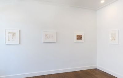 installation view of white paintings framed and hung on two white walls