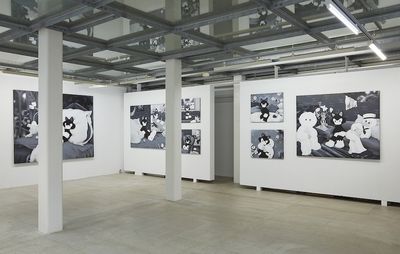 installation view of monochrome paintings of various sizes hung across two walls