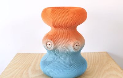 Orange and blue curved sculpture sits on a wooden table