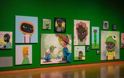 installation view of paintings of various sizes hung on a green wall