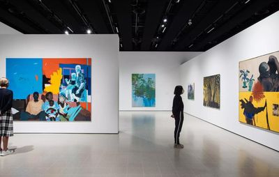 Two large paintings on white walls, each a person observing them in the gallery space