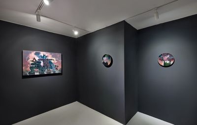 Three paintings are hung on a dark black wall, with a concrete floor. Two of the paintings are circular portraits, while the third is three characters in an apocalyptic scene