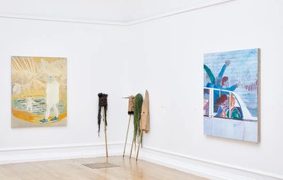 white wall gallery space with two paintings, one blue and one yellow, with sculptures in between the two