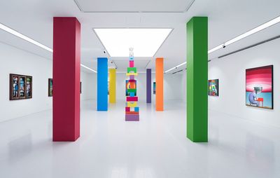 Artwork displayed in a while gallery space, large coloured pillars spread out in the room