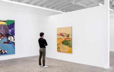 installation view of man looking at one yellow painting whilst another hangs on an adjacent wall