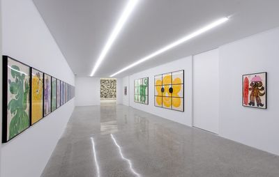 installation view of a long white room with child-like cartoon paintings on the walls
