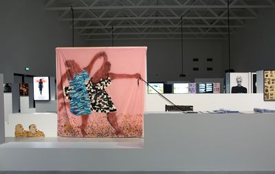large painting on pink cloth set in a large exhibition space amongst other sculptures and canvases