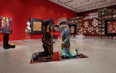 installation view of numerous sculptures, including two figures kneeling centrally facing one another