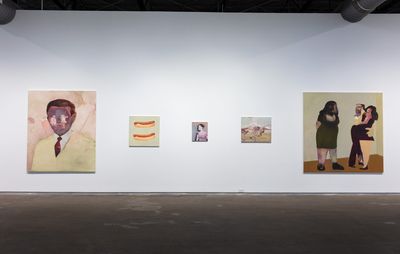 installation view of a white wall with five paintings of varying sizes hung