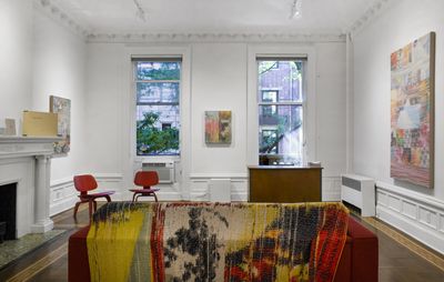 installation view of a white room with furniture in and three artworks on the wall of varying sizes