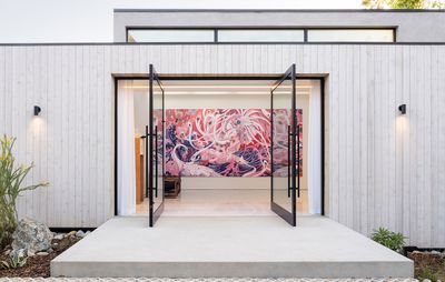 white modern building with open doors and large pink and purple abstract painting inside