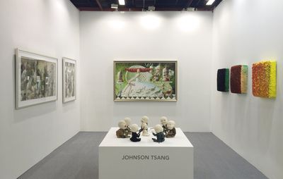 installation view of seven babies heads on a central plinth arranged in a circle formation, surrounded by paintings hung on the wall